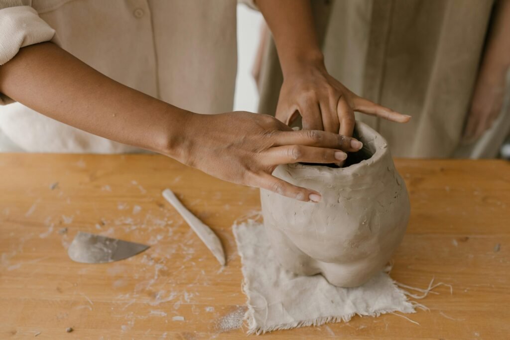Close-up view of hands molding a clay pot, showcasing pottery techniques and craftsmanship.