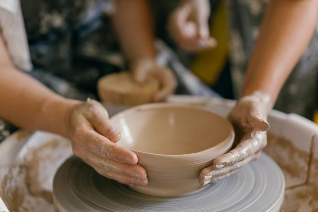 Hands shaping pottery on a spinning wheel, illustrating the art of crafting handmade clay items.